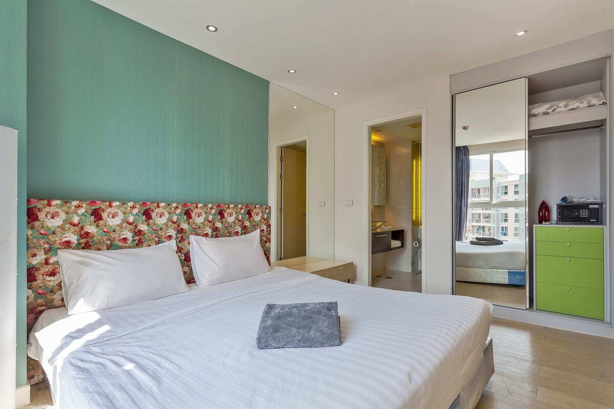 Ein Schlafzimmer mit einem Bett, einem grünen Kleiderschrank und Blick auf die Stadt durch ein Fenster.