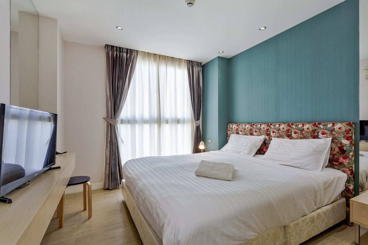 Ein modernes Hotelzimmer mit einem großen Bett, einem Fernseher und einem Schreibtisch.