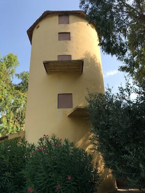 A cylindrical building with a yellow facade, multiple windows, and a wooden balcony. - LE PESCINE - Lecci [SG] (Vada)