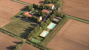 An aerial view of a property with multiple buildings, a swimming pool, and surrounding agricultural fields. - LE PESCINE - Lecci [SG] (Vada)