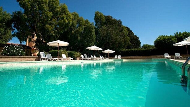 A clear blue pool with white lounge chairs and umbrellas, surrounded by trees. - LE PESCINE - Lecci [SG] (Vada)