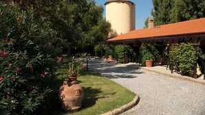 A garden with a water tower, gravel path, and potted plants. - LE PESCINE - Lecci [SG] (Vada)