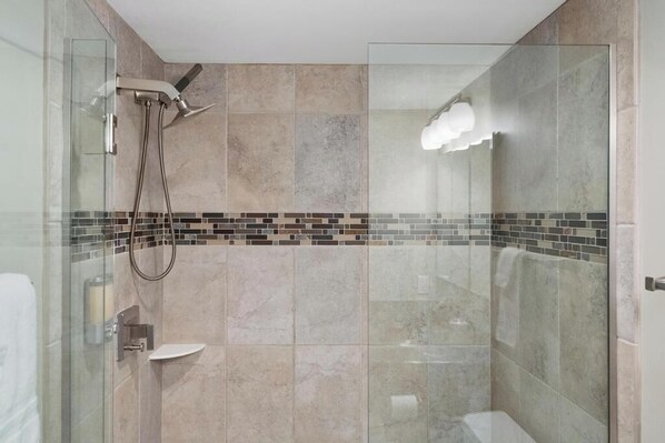 Un bagno moderno con box doccia in vetro, pavimento piastrellato e porta in vetro.