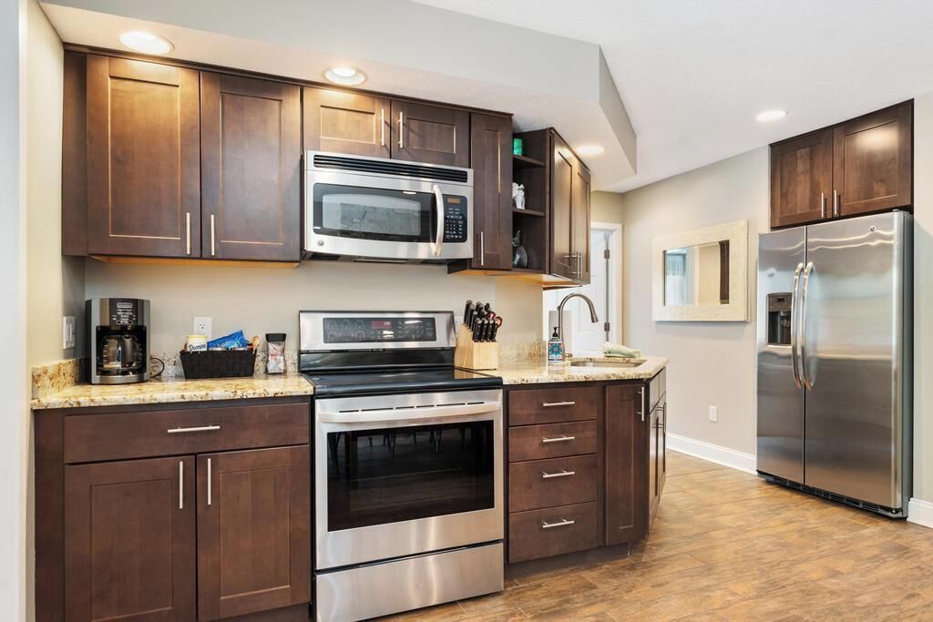 A modern kitchen with dark wood cabinets, stainless steel appliances, and a granite countertop.