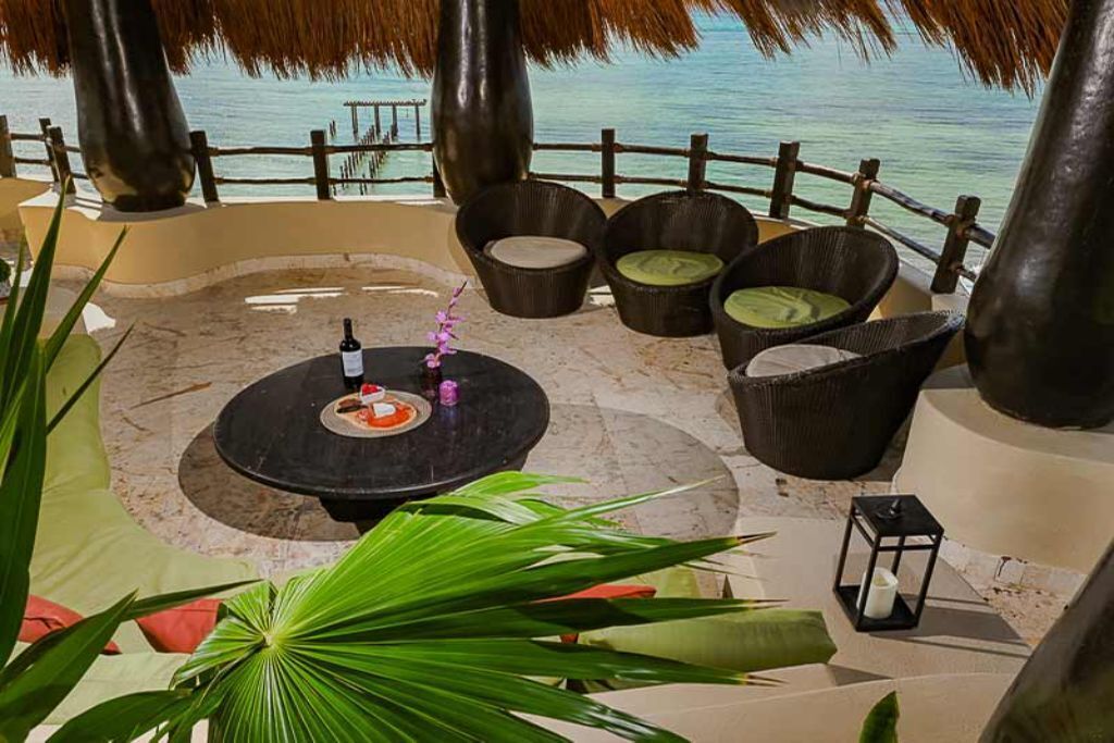 Un espacio al aire libre tropical con una mesa redonda, sillas y vista al océano.