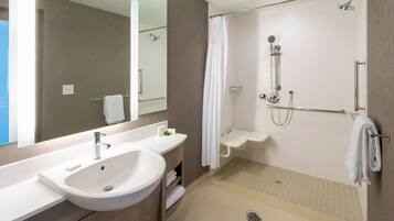 A modern bathroom with a sink, mirror, shower, and towel rack.