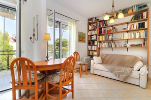 Ein Wohnzimmer mit Esstisch, Stühlen, einer Couch und einem Bücherregal.