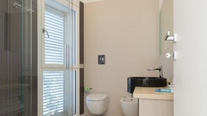 Un baño moderno con cabina de ducha de vidrio, inodoro y lavamanos con espejo.