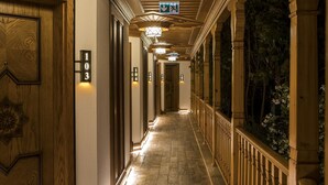 Un pasillo de hotel con puertas de madera, placas con números de habitación y un techo con un diseño decorativo.