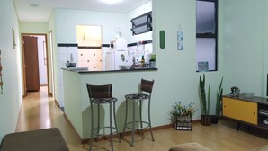 A compact kitchen with a dining area, featuring a central island, two bar stools, and a small seating area with a sofa. - Apartment across from UFV with garage. (Centro)