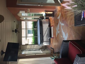 A hotel room with a large window, a flat-screen TV mounted on the wall, a ceiling fan, and a red accent wall. - Beautiful, modern home on golf course near South Padre Island (Laguna Vista)