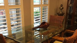 A dining area with a glass-top table surrounded by wicker chairs with cushions. - Beautiful, modern home on golf course near South Padre Island (Laguna Vista)