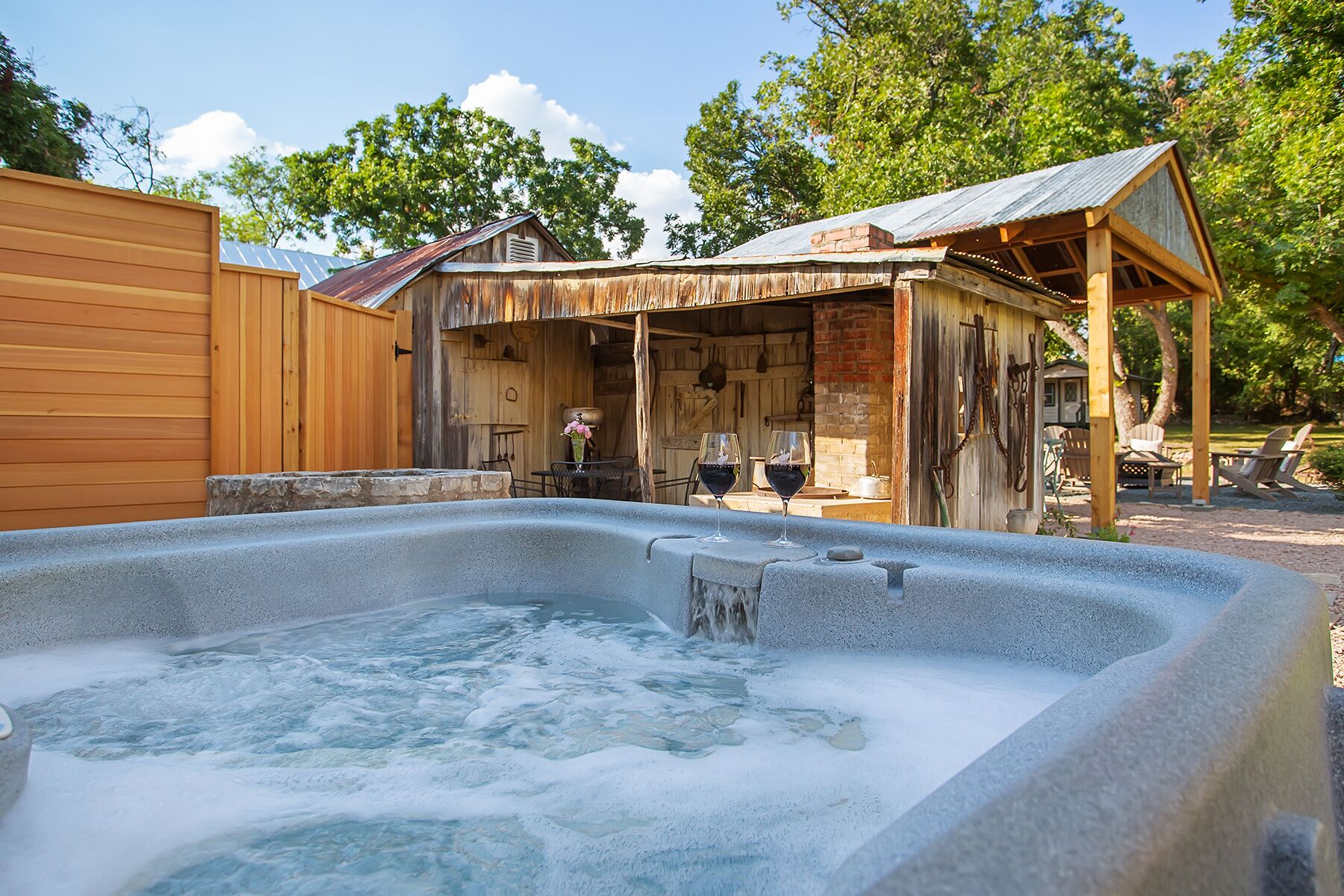 Ein rustikaler Außenbereich mit Whirlpool, einer Holzterrasse und einer überdachten Lounge.