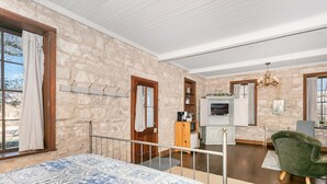 A bedroom with a large bed, a wooden desk, a television, and a green armchair. - Itz Inn Back Courtyard Suite | Sleeps 2 | Next to Hondo's On Main Street (Fredericksburg)