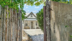 Un sendero de piedra rústico que conduce a una casa blanca con techo a dos aguas, una cerca de madera y un letrero que dice "Acove Cottage 206".