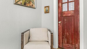 Una silla con un cojín en una habitación con pared blanca y puerta roja.