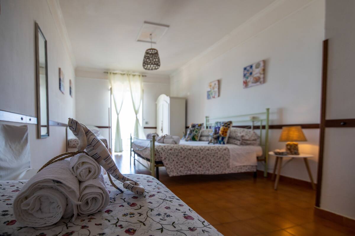 A hotel room with a bed, a bedside table, a lamp, and a window with curtains.