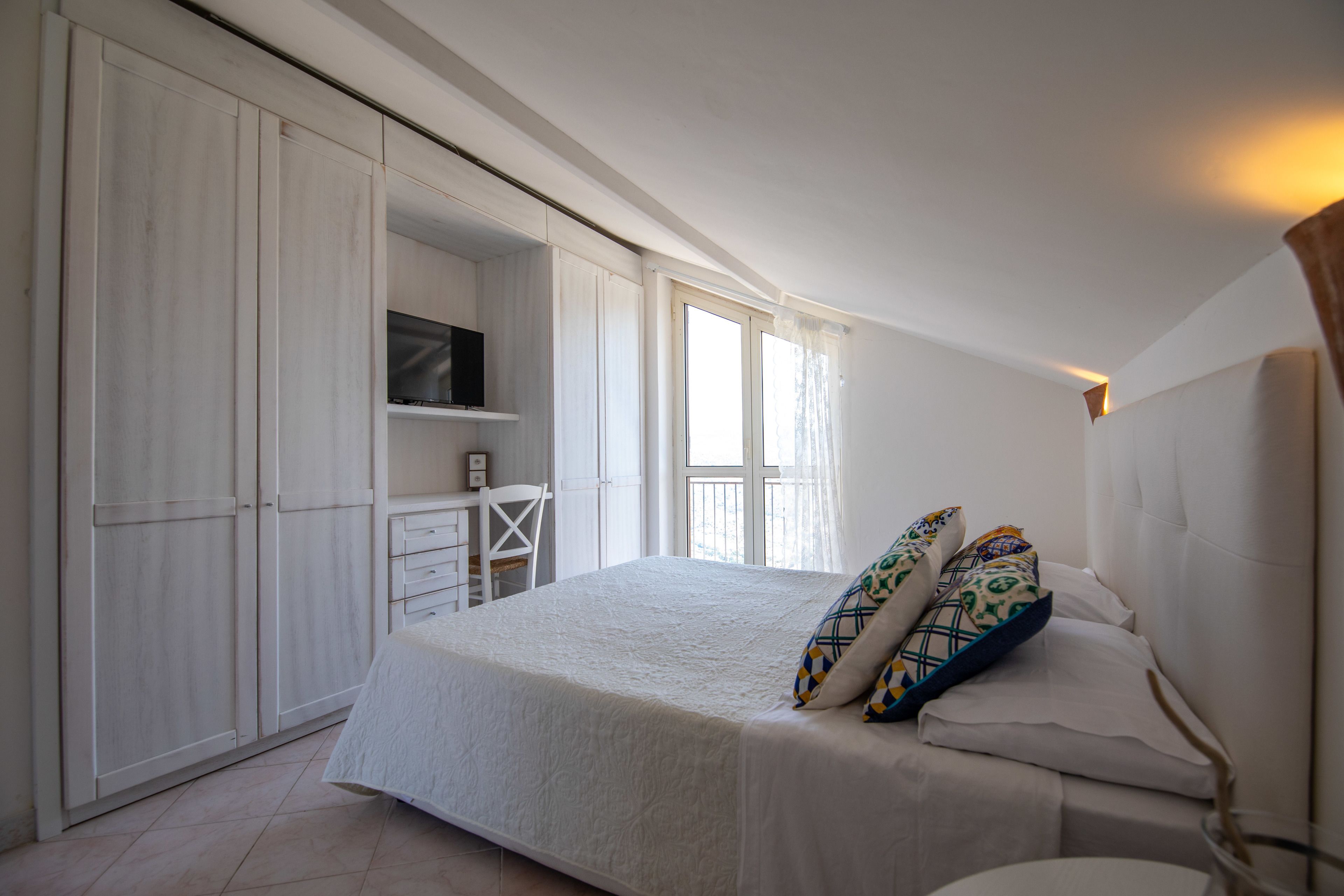 Un dormitorio con cama, televisor, escritorio y armario.