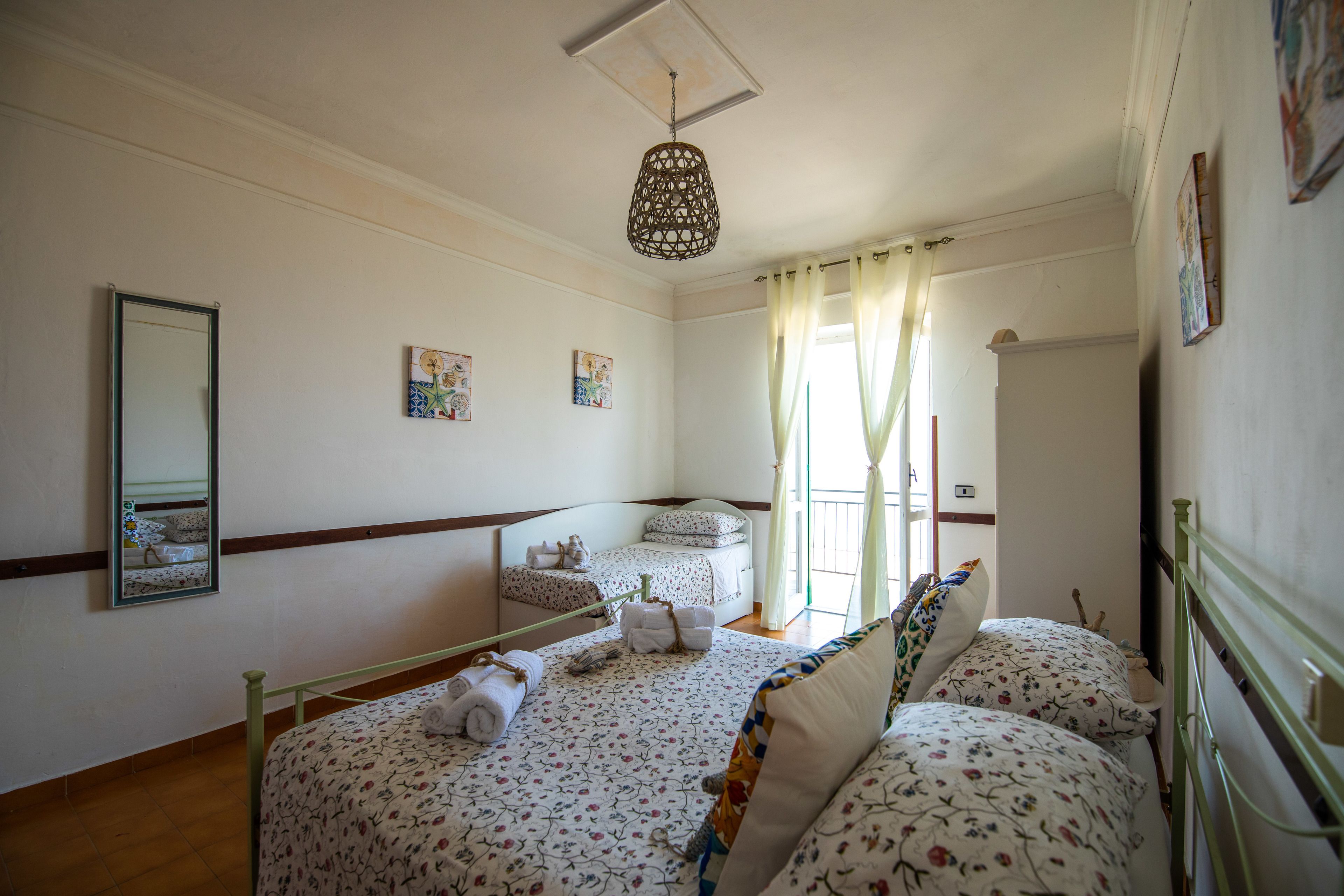 Un dormitorio con dos camas, una lámpara colgante y una ventana con cortinas.