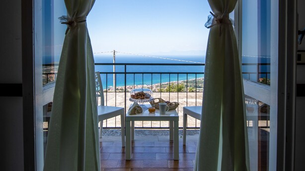 A balcony with a view of the sea, a table with a plate of food, and a chair. - Hotel Ristorante Madonna Della Scala (Castellabate)