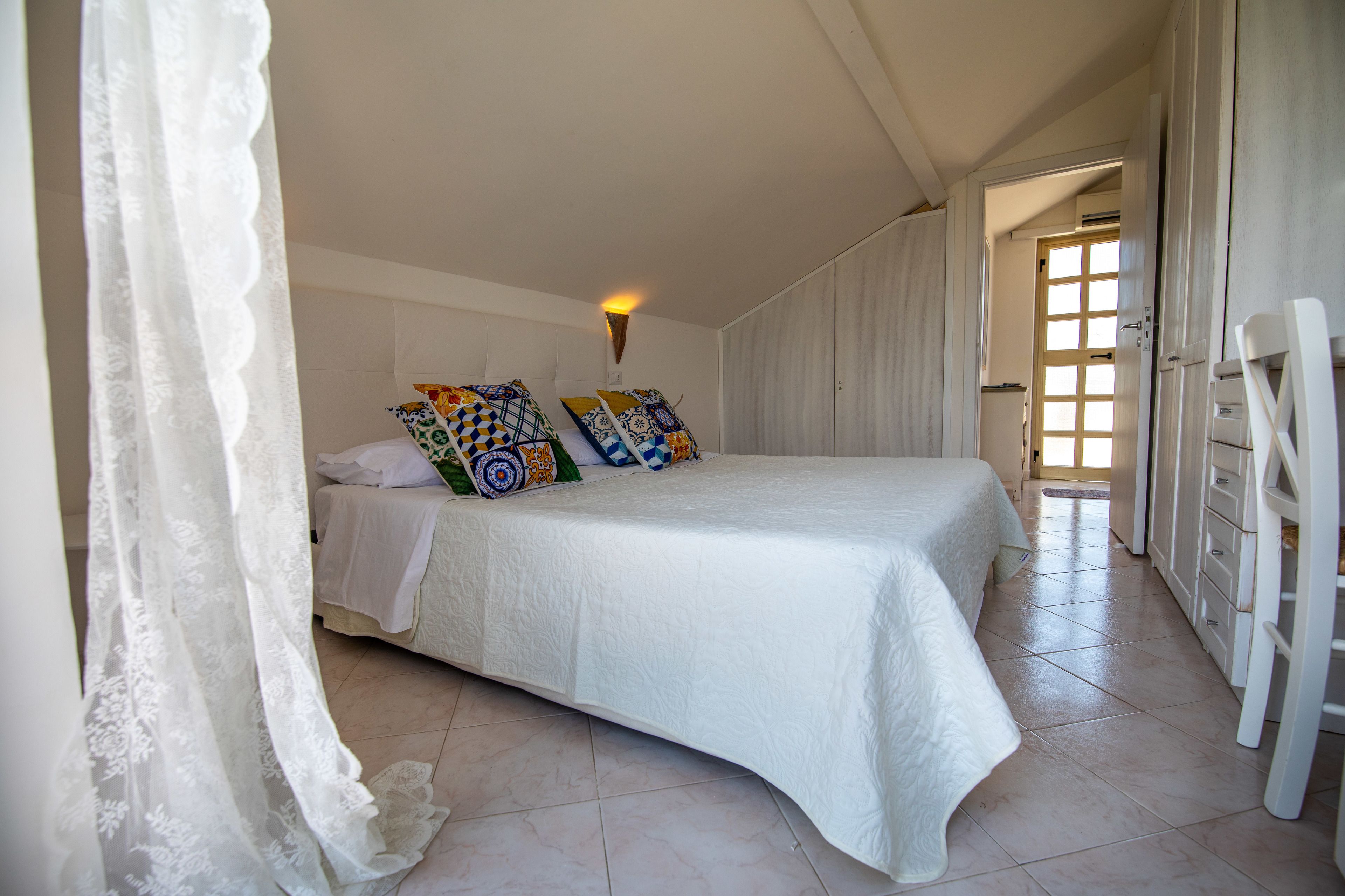 A bedroom with a large bed, a bedside table, and a wardrobe.
