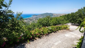 A scenic view of a coastal landscape with a clear sky, lush greenery, and a gravel path. - Hotel Ristorante Madonna Della Scala (Castellabate)
