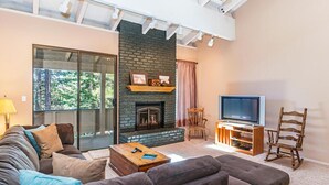 A modern living room with a stone fireplace, a large TV, and comfortable seating.
