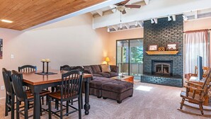 A cozy living room with a fireplace, a dining area with a table and chairs, and a large window providing natural light.