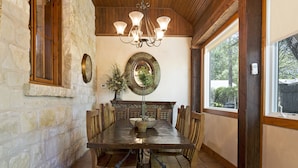Un comedor con pared de piedra, mesa de madera y sillas.