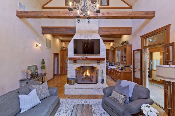 Un salon chaleureux avec une cheminée, des poutres apparentes et un téléviseur.
