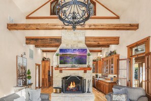 Una sala de estar acogedora con chimenea de piedra, vigas de madera y un candelabro.