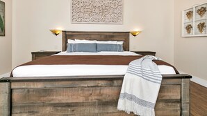 A neatly made bed with a wooden headboard, two bedside lamps, and a decorative wall piece above it.