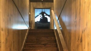 Un escalier en bois, muni d’une rampe, qui mène à une porte située en haut.