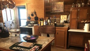 Une cuisine avec des meubles de rangement en bois, une cuisinière et divers ustensiles de cuisine.