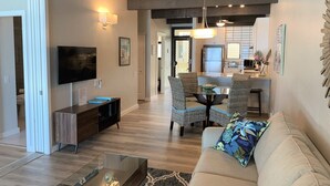 A modern living room with a sofa, coffee table, TV, and dining area with chairs and a table.