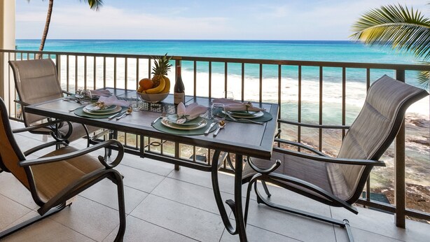 A dining table set for two with a view of the beach and ocean.