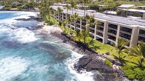 A coastal hotel with a view of the ocean and a parking structure.