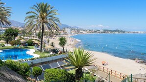 Een resort met zwembad, strand en uitzicht op de bergen.