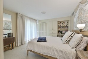 Un dormitorio con cama, escritorio, estantería y lámpara.
