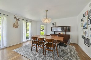 Un comedor con mesa de madera, sillas y una araña.