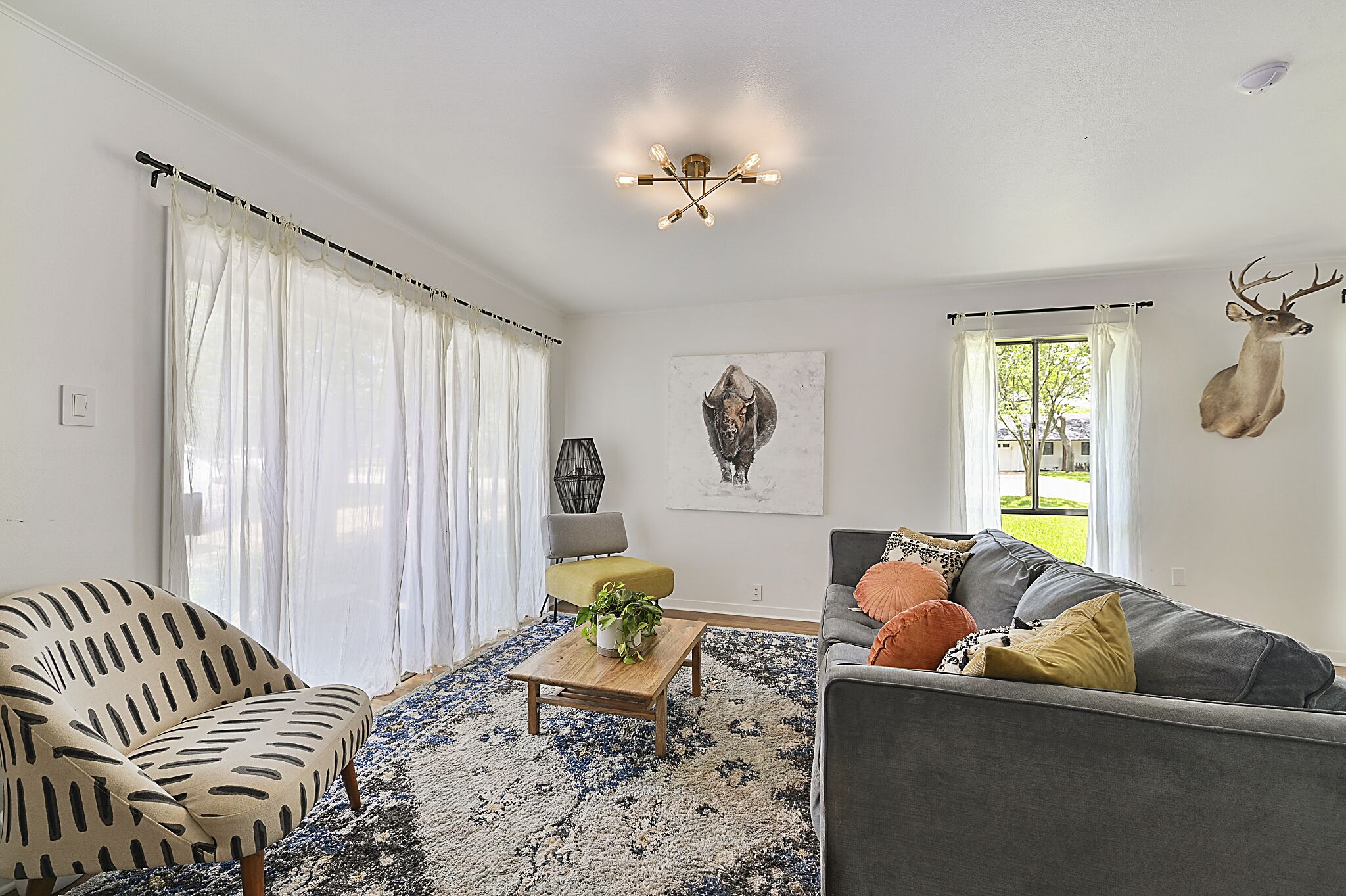 A living room with a sofa, armchair, and a coffee table with a plant.