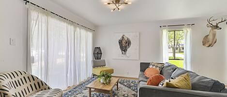 A living room with a sofa, armchair, and a coffee table with a plant.