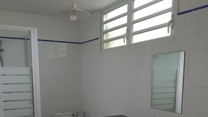 Ein Badezimmer mit Dusche, Toilette und zwei Waschbecken.