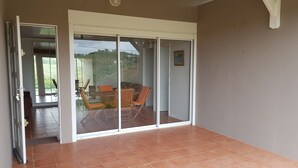 Ein Zimmer mit einer Schiebetür, die auf eine Terrasse mit Tisch und Stühlen führt.