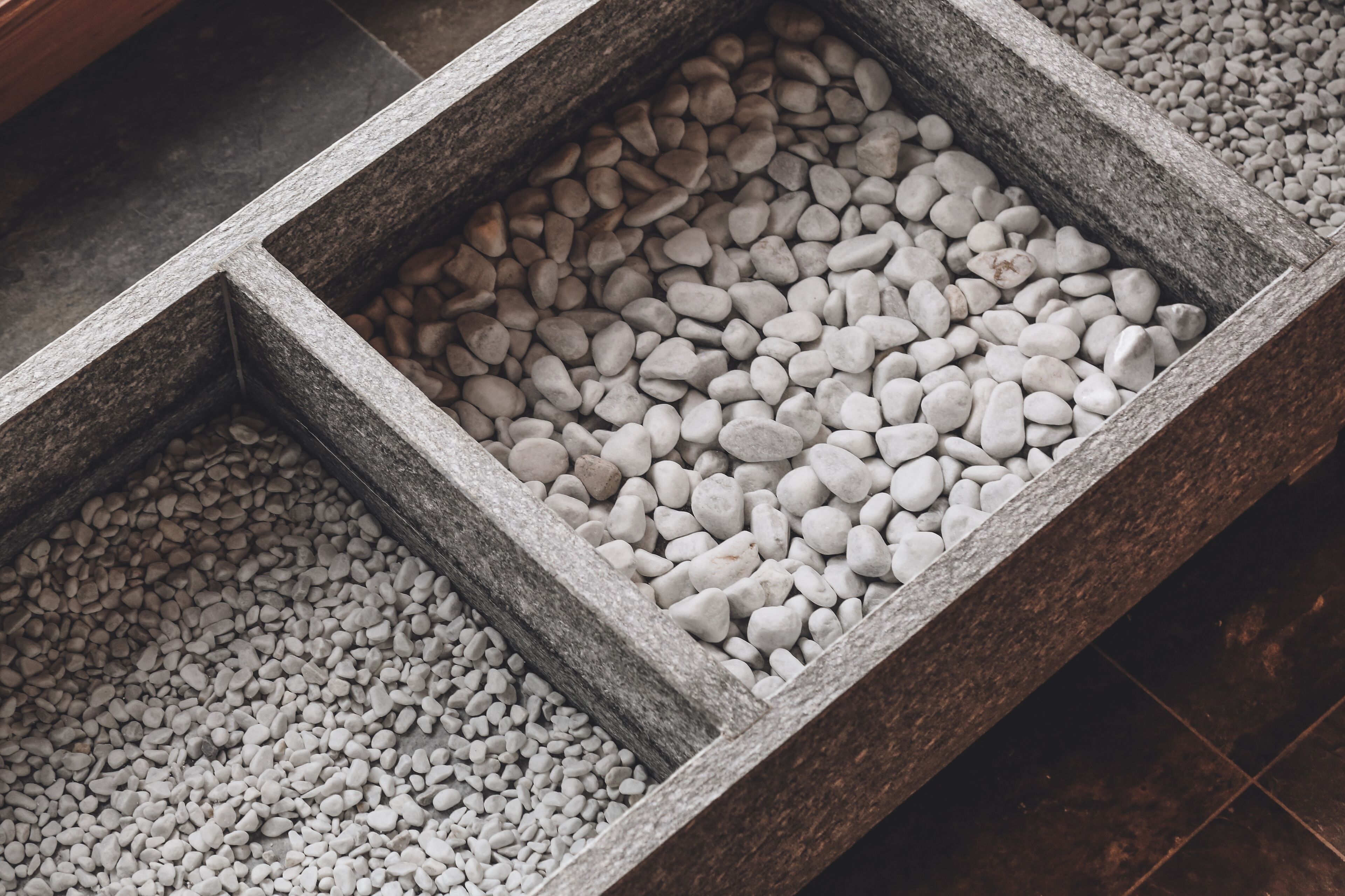 A close-up of a stone planter with white pebbles.
