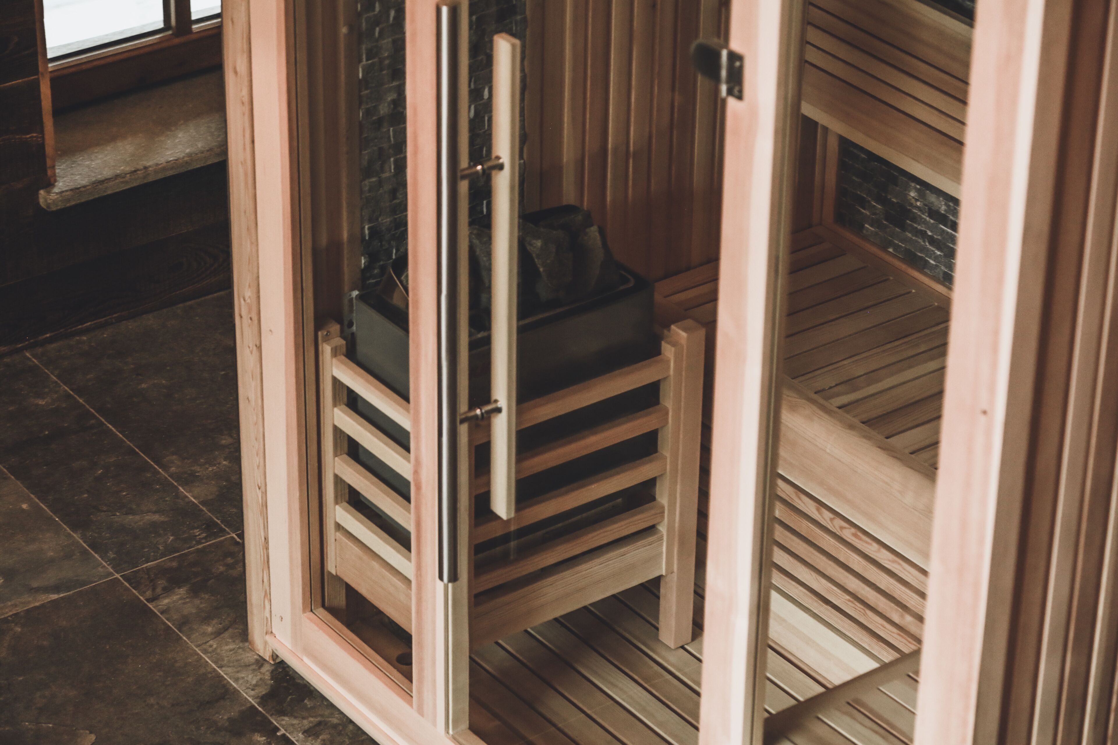 Una sauna con una panca in legno e una porta.
