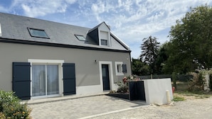 A modern two-story house with a grey roof, large sliding glass doors, and a small garden area. - New house with beautiful sea view (Groix)