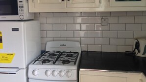 Een keuken met witte kastjes, een magnetron, een fornuis en een koffiezetapparaat.