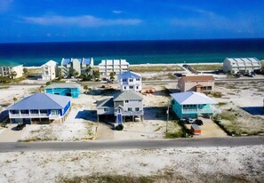 Et kysthotel med flere bygninger, udsigt til stranden og en vej i forgrunden.