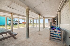 Un espacio exterior techado con piso de concreto, pilares de madera y una mesa de picnic.